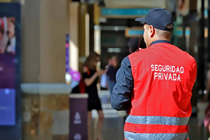 Guardia con chaleco rojo de seguridad privada supervisando un espacio comercial